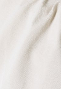 Off-white tyg med en slät, strukturerad yta, som visar subtila ribbade mönster. Mjuk och formbar material.