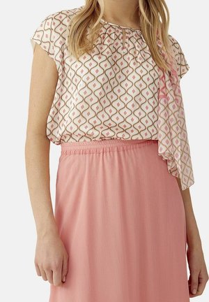 Blouse avec un motif ondulé en rose et beige ; manches courtes et décolleté en forme de clé. Jupe en rose doux, avec une finition texturée.