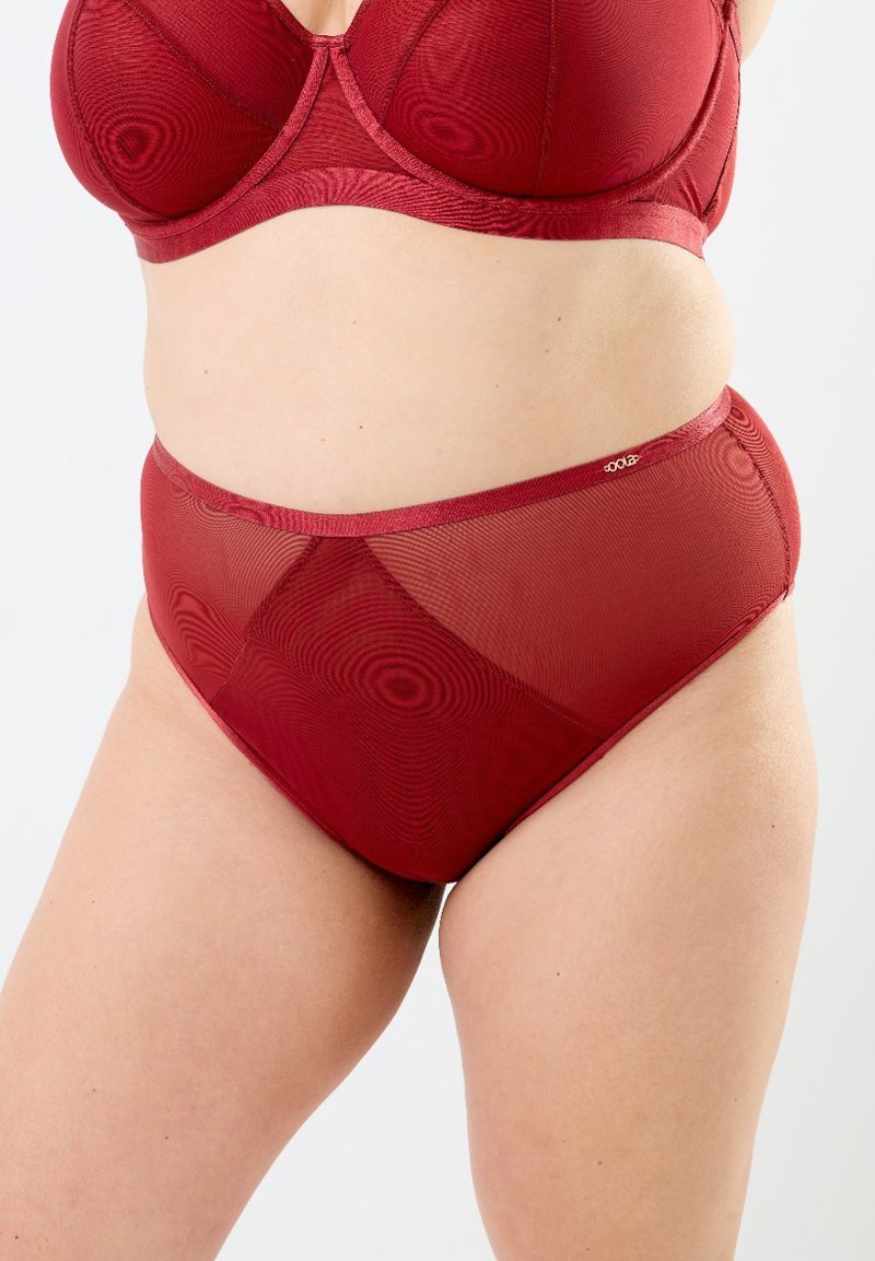 Röd bh och högmidjad trosuppsättning i genomskinligt meshtyg. Har en slät kant och ett subtilt vågigt mönster genom hela.