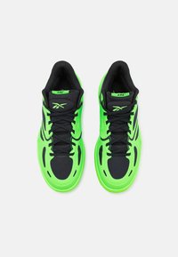 Grüne und schwarze Sport Sneakers zeichnen sich durch ein schlankes Design, Mesh- und Synthetikmaterialien aus, mit markanten Kurven und Schnürverschluss.