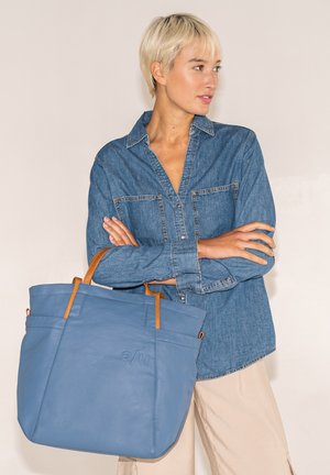 Blaue Leder-Tote mit braunen Griffen und geprägtem Logo, ausgestattet mit einer strukturierten Form und äußeren Taschen. Stilvolle und funktionale Designdetails.