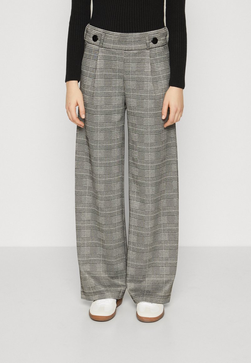 Pantalons à jambes larges en motif vichy noir et blanc. Fabriqués en tissu texturé avec deux poches avant et des boutons noirs à la taille.