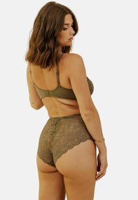 Ensemble de lingerie vert olive comprenant un soutien-gorge lisse avec des bretelles ajustables et des culottes en dentelle taille haute avec un motif floral et des bords festonnés.