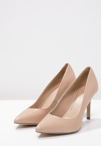 Pompes à talons hauts beiges en cuir lisse. Elles présentent un bout pointu, un design épuré et un talon aiguille élancé.