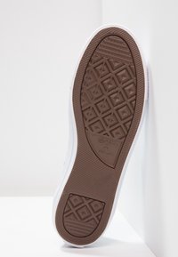 Białe sneakersy z brązową gumową podeszwą z diamentowym wzorem i teksturowymi akcentami. Logo marki wytłoczone na podeszwie.