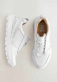 Hvide sneakers lavet af struktureret læder med en polstret sål. Funktioner inkluderer snørebånd, en forstærket hæl og minimalistiske designelementer.