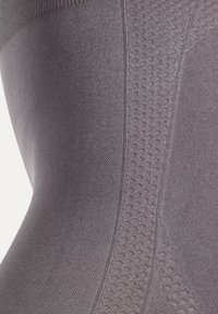 Leggings gris sans couture avec des motifs texturés, une finition lisse et une coupe ajustée sur les côtés. Le matériau semble extensible et respirant.