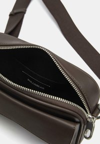 Borsa a tracolla in pelle marrone con apertura con cerniera, forma strutturata e etichetta interna. Include una tracolla in tessuto per un facile trasporto.