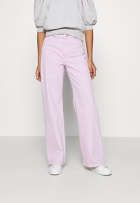 Jeans a gamba larga lavanda realizzati in denim con cinque tasche, passanti per cintura e chiusura frontale con bottone, abbinati a un sweatshirt grigio con maniche a sbuffo.