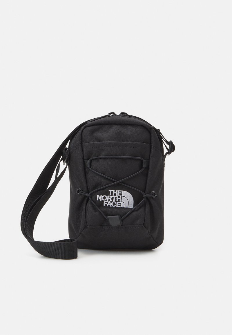 Black crossbody bag made of durable material. Features a logo, zip closure, adjustable strap, and elastic bungee detailing on the front.
