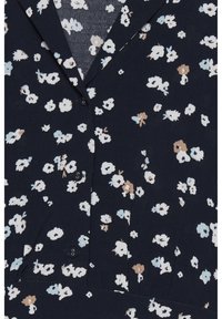 Marinblå plagg med små vita, ljusblå och beige blommönster, med krage och tre synliga marinblå knappar framtill.