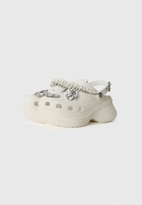 Vita träskor med dekorativa rhinestones och pärldetaljer, med en kraftig sula, rund tå och bakrem för en säker passform.