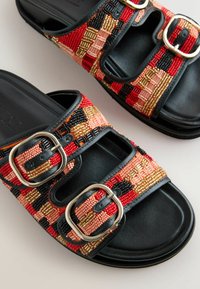 Sandali neri senza lacci con due cinturini regolabili caratterizzati da motivi di perline rosse, oro, nere e rosa e fibbie d'argento.