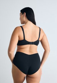 Schwarzer BH und hochgeschnittene Unterhose aus glattem Stoff, mit verstellbaren Trägern, einemverschluss und nahtlosem Design.