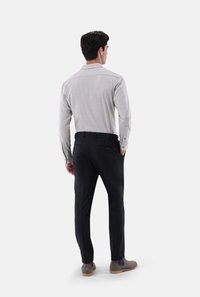 Helles graues Langarmhemd mit Kragen, kombiniert mit dunklen Hosen. Glatter Stoff, taillierte Passform und ein dezentes Karomuster. Braune Stiefeletten.