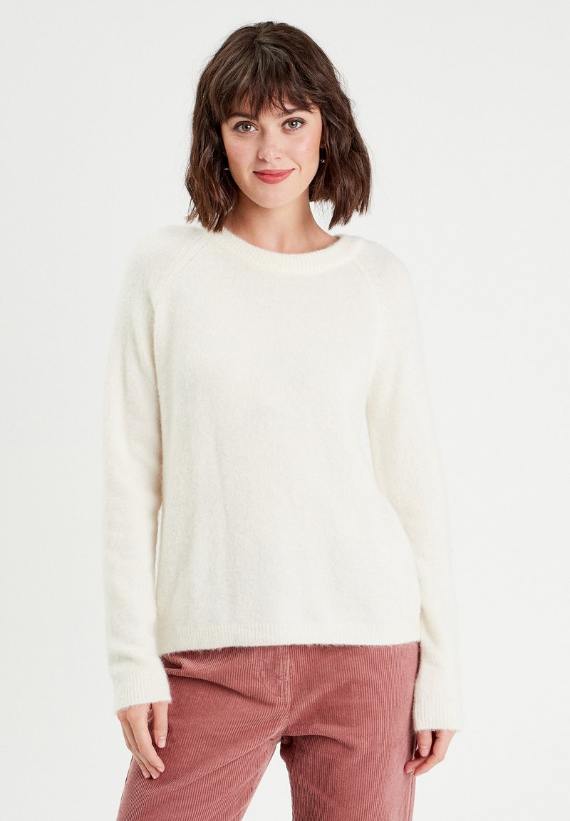 Pull blanc et duveteux à manches longues avec un col côtelé. Le tissu texturé a une apparence douce. Assorti à un pantalon en velours côtelé rose.