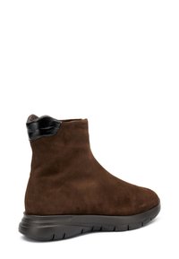 Stivale alla caviglia in suede marrone con punta arrotondata, dotato di un accento in pelle nera sul collo e una suola in gomma nera testurizzata.