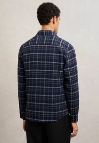 Camicia di flanella a quadri blu e neri, con colletto, maniche lunghe, polsini con bottoni e orlo curvo. Tessuto morbido e design strutturato.