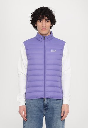 Lyslilla puffer vest med høj krave, fuld lynlås og EA7-logo; struktureret med vandrette syninger; båret over en hvid langærmet skjorte.