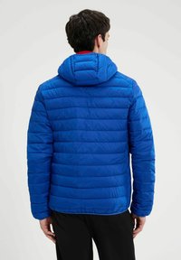 Giacca blu imbottita con cappuccio, caratterizzata da una trapuntatura orizzontale, texture liscia e design aderente. La vista posteriore mostra il dettaglio dell'orlo e delle maniche.
