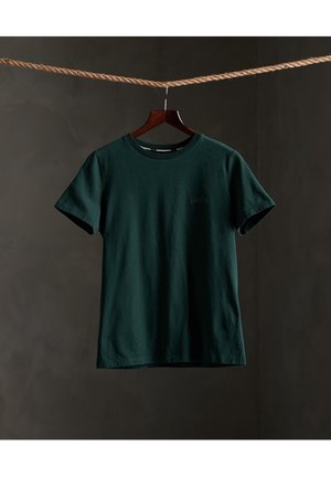 Ciemnozielona bawełniana koszulka z okrągłym dekoltem i krótkimi rękawami, z delikatnym logo na przodzie i gładką, czystą teksturą.