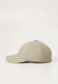 Boné de beje feito de algodão com aba curva, seis orifícios de ventilação e detalhe do logótipo bordado na frente.