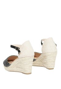 Sandali wedge neri e beige con tacco in juta intrecciata, punta aperta, cinturino alla caviglia e parte superiore in tessuto testurizzato. Sottile motivo a scacchi sul tacco.