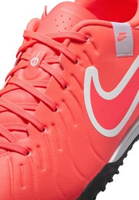 Erkki roosa tekstuuriga jalgpalliking, millel on valge Nike Swoosh, kangaslaced ja tugevdatud varbakaitse ventilatsiooniavadega.