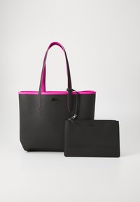 Zwarte tote bag met textuur, voorzien van een roze rand en handvatten, met een afneembare zwarte pouch met rits. Minimalistisch ontwerp, subtiele branding.