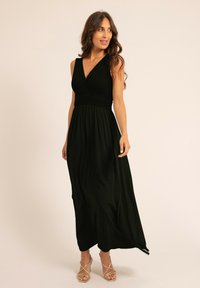 Robe maxi noire avec un buste texturé en style portefeuille et une taille smockée. Comprend une jupe fluide et des talons fins à lanières.