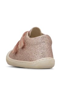 Scarpa per bambini glitterata di colore rosa con una texture morbida, cinturino in velcro e suola in gomma flessibile, che presenta un design arrotondato.