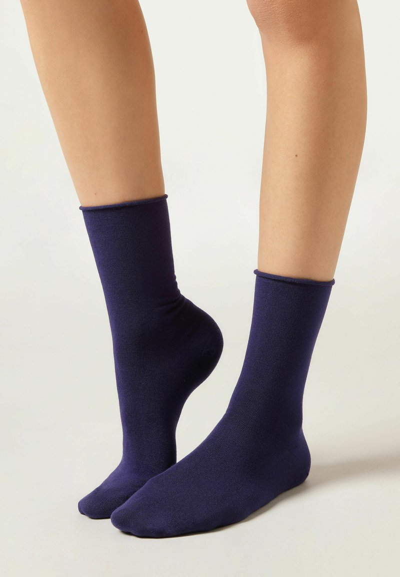 Calze blu navy realizzate in un tessuto morbido e elastico, con un bordo a coste. Il design presenta una forma aderente e una chiusura della punta senza cuciture.