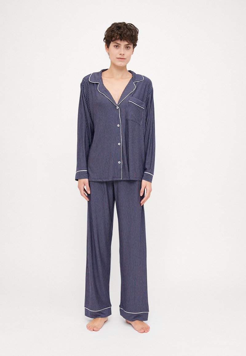 Navy blue striped pajama set with long sleeves, button-up shirt, and wide-leg pants, featuring white trim on the cuffs and collar.