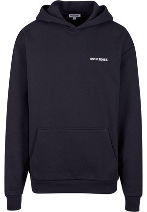 Marinblå hoodie med känguruficka, snörning i huvan och vit text "9N1M SENSE." broderad på bröstet. Mjuk tygstruktur.