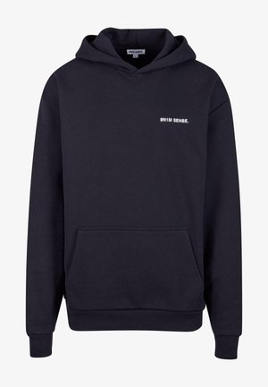 Merinovihreä huppari, jossa on kengurupocket, kiristettävä huppu ja valkoinen teksti "9N1M SENSE." brodeerattuna rinnassa. Pehmeä kangas.