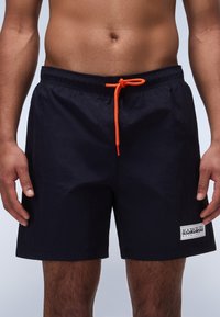 Jūriniai maudymosi šortai, tamsiai mėlynos spalvos, su elastine juosta, oranžiniu raišteliu ir mažu baltu logotipo ženkleliu kairėje pusėje. Lengvas, tekstūruotas audinys.
