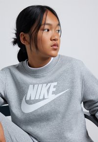 Grijze sweatshirt van een katoenmix, met een groot wit "NIKE"-logo en swoosh. De ronde hals en geribbelde manchetten voegen detail toe.
