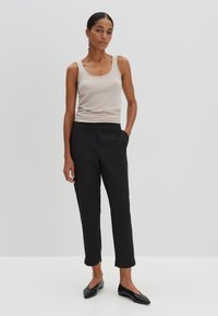 Beige tank top and black trousers. The top is fitted, sleeveless, with a scoop neckline. The trousers are cropped, with a smooth texture and side pockets.