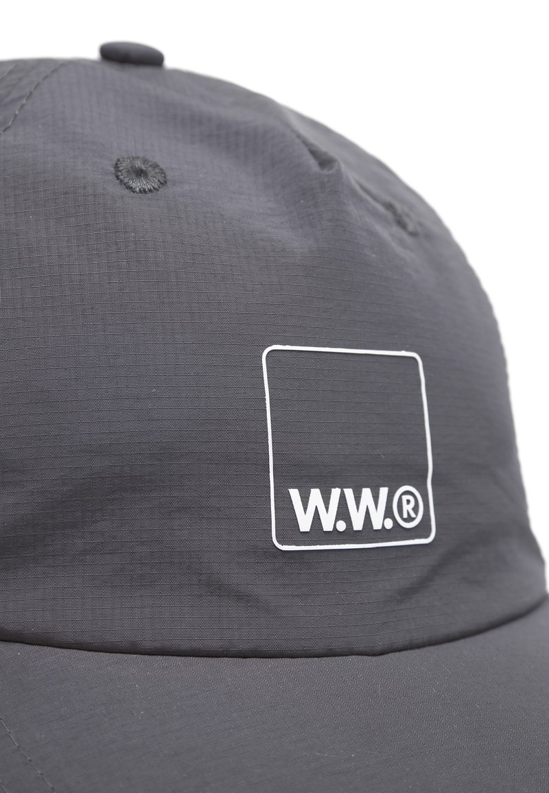 Cappellino da baseball grigio scuro con fori di ventilazione cuciti e un logo quadrato bianco con la scritta "W.W.®" sul pannello frontale.
