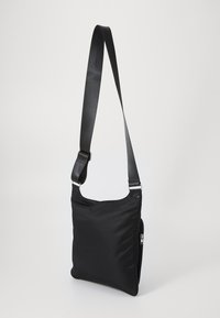 Borsa a tracolla nera in nylon con forma piatta, tracolla regolabile, accessori in argento e tasca con zip. Texture liscia, design minimalista.