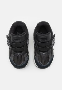 Chaussures de sport noires en matériaux mesh et synthétiques, dotées d'une fermeture à Velcro à deux sangles, d'un bout rond et d'une semelle légère.