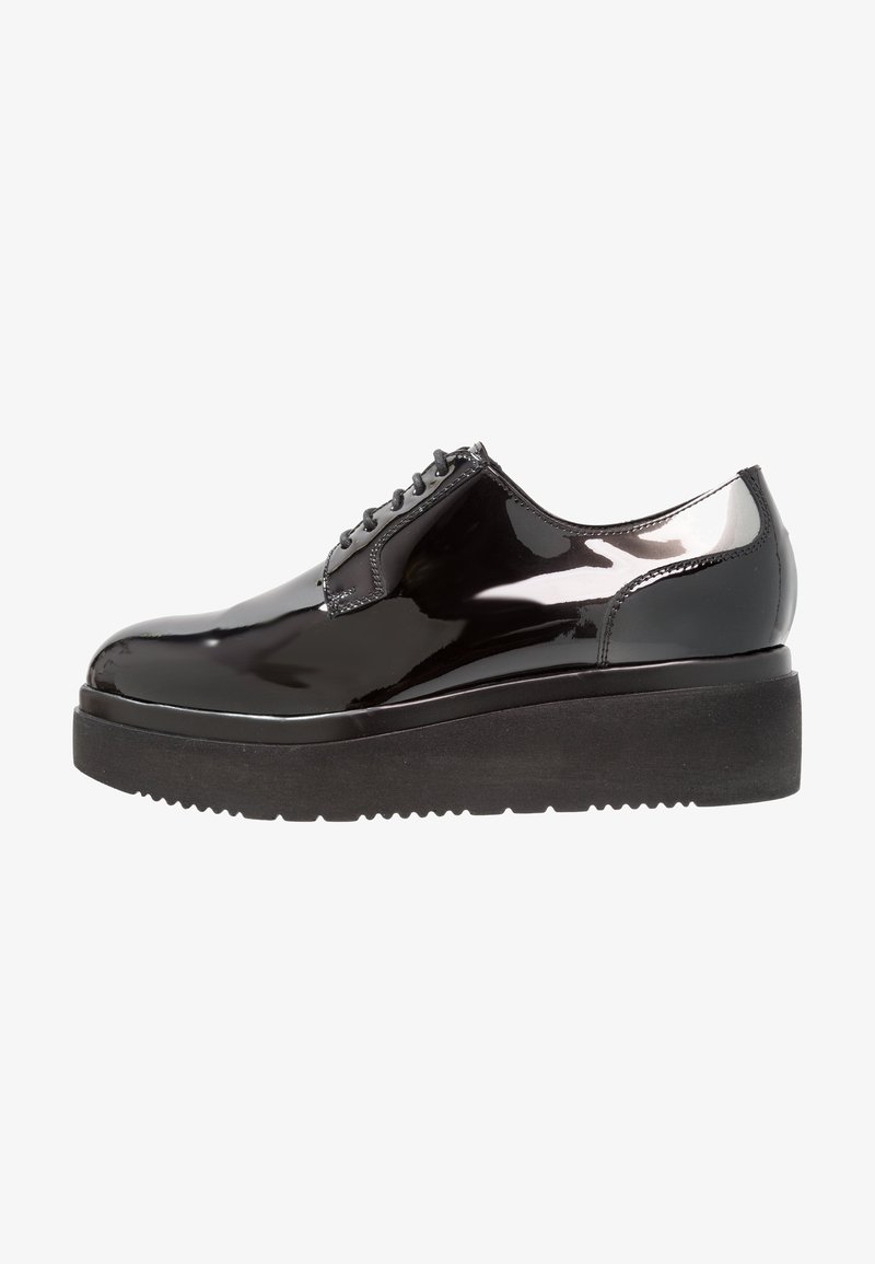 Chaussure plateforme en cuir verni noir avec semelle épaisse noire et lacets noirs, talon bas et finition lisse et brillante.
