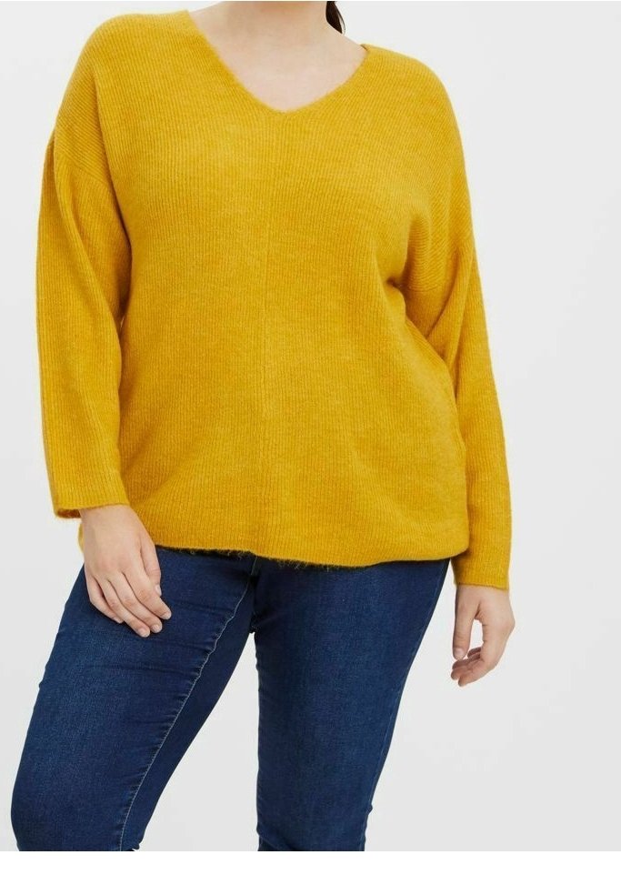 Maglione a coste giallo senape con scollo a V e spalle cadute, caratterizzato da una vestibilità rilassata e orlo grezzo. Abbinato a jeans blu scuro.