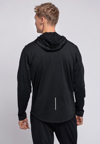 Zwarte lange mouwen sport hoodie met een voorzak, een capuchon en reflecterende details op de rug. Gemaakt van een soepele, flexibele stof.