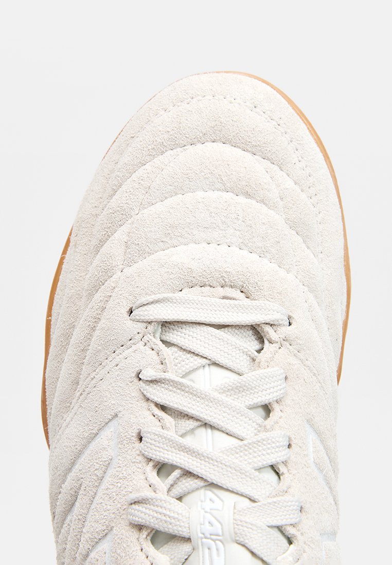 Lichtgrijze suède sneaker met een gemêleerde bovenkant, witte veters en een gumrubberen zool. Kenmerkt gestikte accenten en een afgerond teenontwerp.