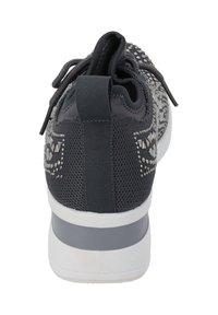 Sneaker nera in rete con borchie decorative sul tallone, colletto imbottito e suola in gomma grigia con una banda bianca accentuata.
