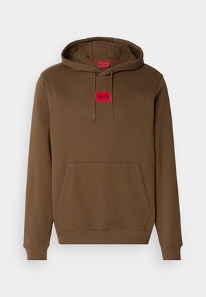 Haut à capuche brun avec cordon de serrage, poche kangourou à l'avant, et une étiquette rectangulaire rouge portant "HUGO" centrée sur la poitrine.