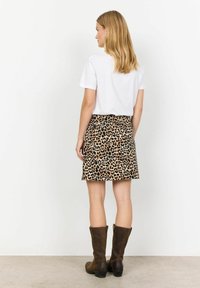 Minirok met luipaardprint van stof, met een aansluitende taille en rechte snit, gecombineerd met bruin leren laarsjes tot aan de knie.