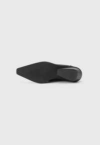 Zapato de tacón alto negro con punta afilada y parte superior lisa. Agarre texturizado en el tacón, silueta elegante y sin acentos decorativos visibles.