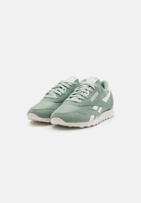 Green sneakers made of suede and mesh, featuring white accents, a lace-up design, and a textured rubber sole for traction.